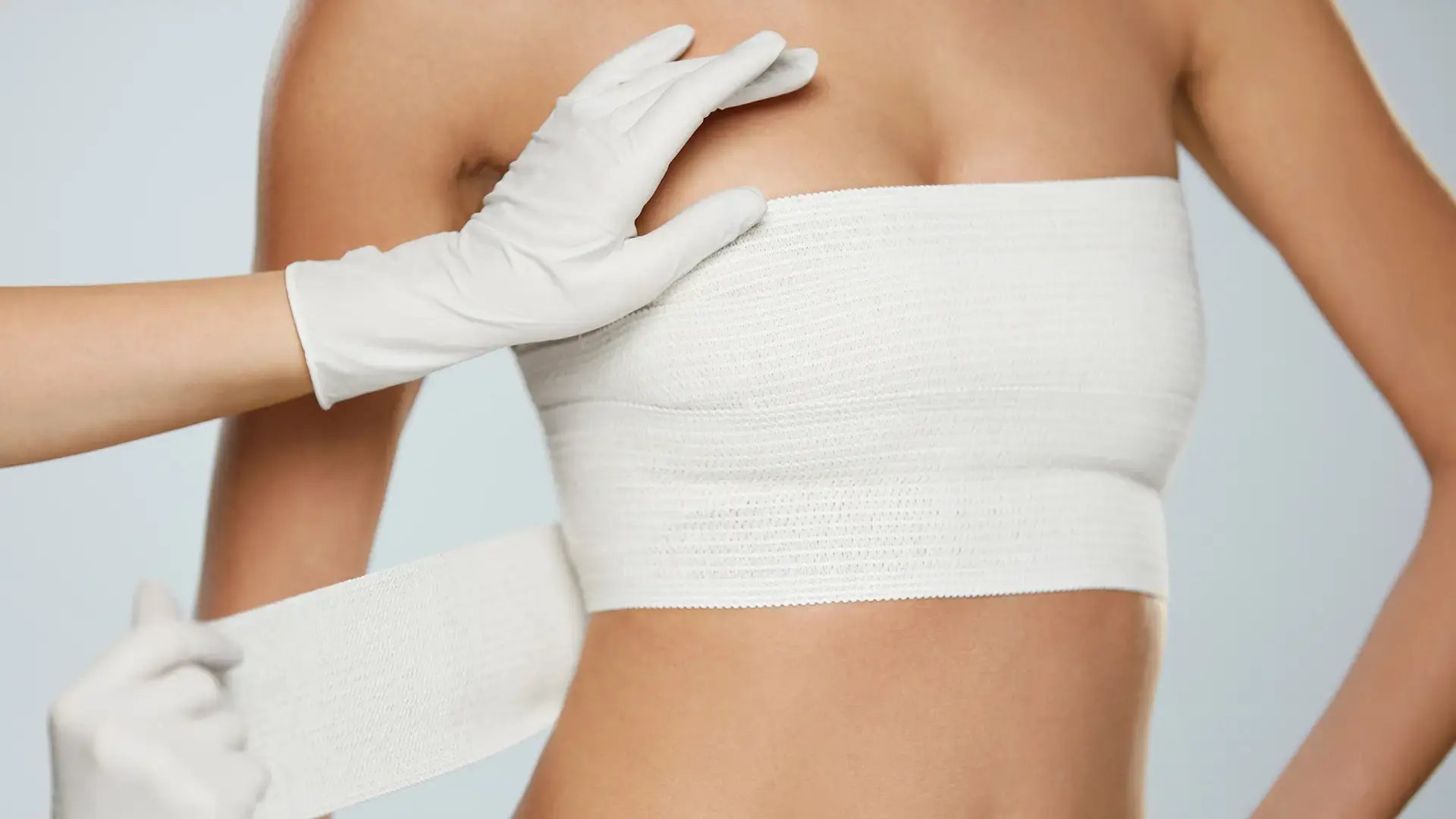 Plastic-Surgery_-Doctor-Hands-Wrapping-Female-Breast-In-Bandage